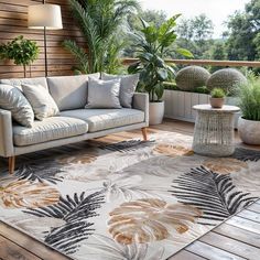 a living room area with couches and potted plants on the balcony overlooking trees