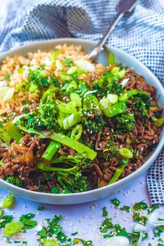 a bowl filled with rice and broccoli on top of a blue table cloth