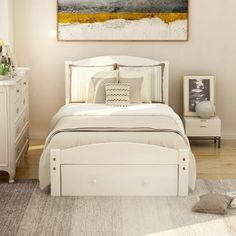 a white bed sitting in a bedroom on top of a wooden floor next to a dresser