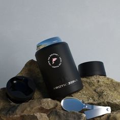 a black canister sitting on top of a rock next to a pair of scissors