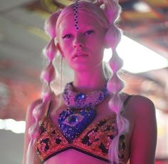 a woman with blonde hair and braids wearing an elaborate outfit in a room full of lights