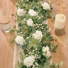 the table runner is decorated with white flowers and greenery