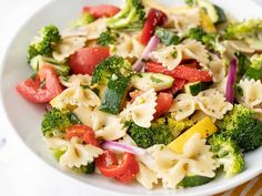 a white bowl filled with pasta and veggies on top of a yellow table cloth