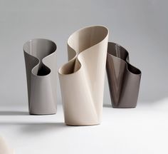 three vases with curved sides on a white surface, one in grey and the other in beige