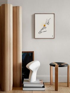 a white chair sitting next to a table in a living room under a framed art piece