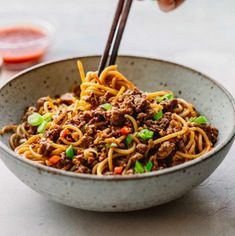 a bowl filled with noodles, meat and veggies on top of a table