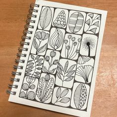 a notebook with an image of flowers and leaves drawn on the cover, sitting on a wooden table