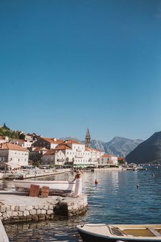 a woman standing on the edge of a dock next to some boats in the water