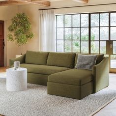 a living room with a large green couch and white rug on the floor next to a window