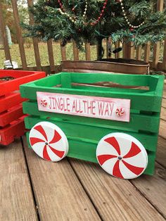 a green wagon sitting on top of a wooden deck next to a red box filled with candy canes