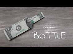 an origami bottle made out of one dollar bill on a wooden surface with the word bottle written below it