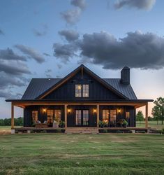 a large black house sitting on top of a lush green field