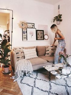 a woman standing on the back of a couch in a living room next to a coffee table