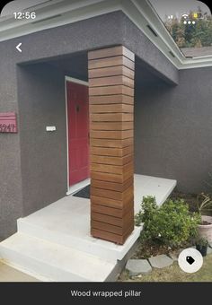 a red door is on the side of a gray house with steps leading up to it