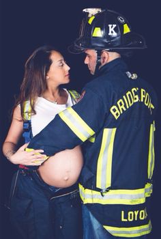 a pregnant woman is standing next to a fireman with her belly wrapped around the man's waist