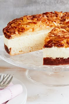 a cheesecake on a glass cake plate with one slice cut out and ready to be eaten