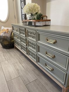 a large gray dresser with gold handles and knobs on it's drawers in a living room