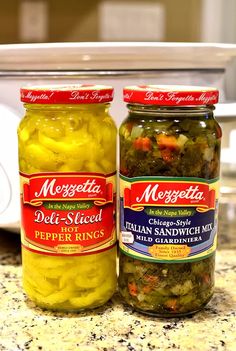 two jars of pickles sitting on top of a counter