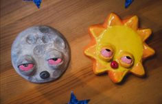 two clay animals sitting next to each other on top of a wooden table with blue stars