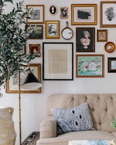 a living room filled with lots of framed pictures on the wall next to a couch