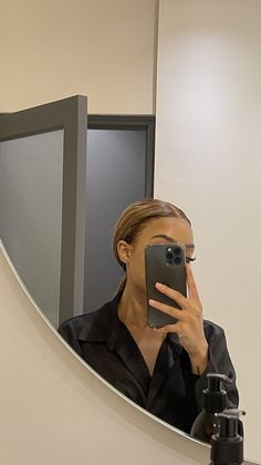 a woman taking a selfie in front of a mirror with her cell phone up to her face