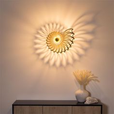 a white vase sitting on top of a wooden table next to a wall mounted light