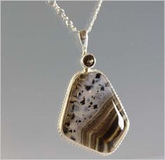 This necklace is made with a gorgeous hand cut and polished Montana Agate. The Montana Agate shows beautiful dendrites on one half of the stone while the other half is stunning banding that flows with the cut of the stone. The stone has been bezel set in sterling silver and accented with a sterling silver tube set faceted smokey quartz gemstone. The pendant is on a 16 inch figure-8 sterling silver chain. Montana Agate, Rock Jewelry, The Other Half, One Half, Other Half, Agate Necklace, Stone Work, Agate Pendant, Smokey Quartz