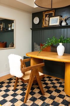 a room with a table, chair and bookshelf on the wall next to it