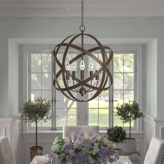 a chandelier hanging over a dining room table with flowers in the vases