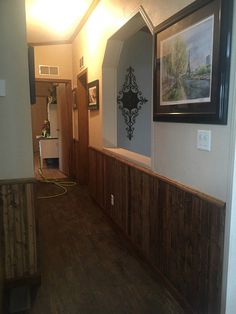 a hallway with wood paneling and framed pictures on the wall, along with a hardwood floor