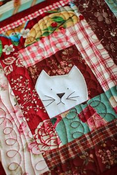 a close up of a patchwork quilt with a cat face on it's side