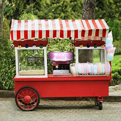 a red and white cart with some food on it's side in front of a tree