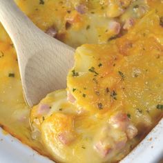 a wooden spoon in a casserole dish with ham and cheese