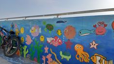 a motorcycle parked next to a colorful wall with fish and sea creatures painted on it