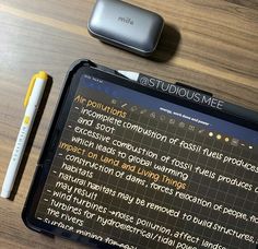 an electronic device sitting on top of a wooden table next to a pen and paper