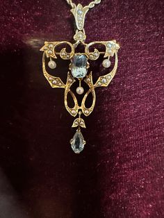 "For you consideration, a stunning 16K (yes, that is correct) yellow gold pendant pin combination.  This multipurpose vintage piece is hallmarked 16K (ct) and can be used as a stunning pendant or brooch.  The intricate design reflects the incredible workmanship.  The center oval blue topaz measures 8mm x 6mm, while the teardrop shape dangle topaz measures 8mm x 4 1/2mm. Gray and white seed pearls throughout the setting provide a wonderful contrast to the blue stones.  The fold over portion of the bail allows for the transition from pendant to brooch.  The 14K yellow gold twisted rope chain measures 18\". Both pieces weigh in at a hefty 8.42 grams.  This is a incredibly beautiful piece!" Heirloom Yellow Gold Gemstone Brooches, Ornate Gold Brooch With Rose Cut Diamonds, Ornate Gold Brooches With Rose Cut Diamonds, Victorian Yellow Gold Brooches With Gemstone, Elegant Gold Necklace With Brooch, Anniversary Pendant Necklaces With Brooch Detail, Anniversary Pendant Necklace With Brooch Detail, Heirloom Blue Necklaces For Weddings, Antique Yellow Gold Brooches With Gemstone