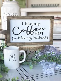 two coffee mugs sitting next to a sign that says i like my coffee, just like my husband