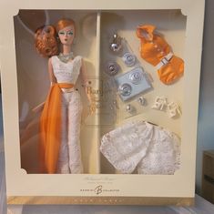 a barbie doll in a box with clothes and other items on it's side