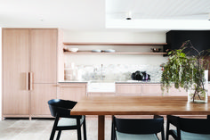 a wooden table with chairs around it and a plant on the counter in front of it