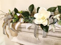 a fireplace mantel decorated with white flowers and greenery