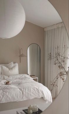 a white bed sitting under a round mirror