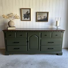 a green dresser with two pictures on the wall