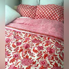 a bed with red and white bedspread on top of it next to pillows