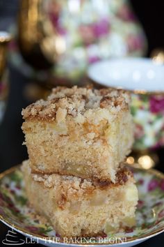 two pieces of cake sitting on top of a flowered plate next to cups and saucers