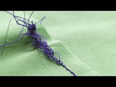 a close up of a purple thread on a green cloth