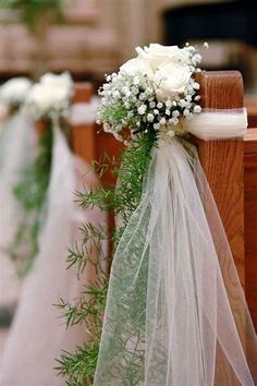 white flowers and greenery are tied to pews