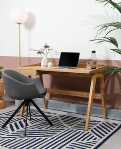 a laptop computer sitting on top of a wooden desk next to a potted plant