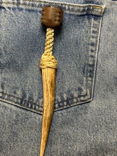 a wooden stick sticking out of the back pocket of someone's jean pants with a rope attached to it