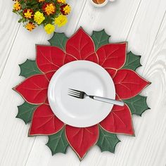 a white plate topped with a red poinsetti on top of a wooden table