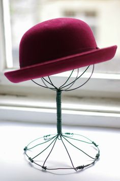 a red hat is sitting on a wire stand